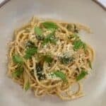 Creamy zucchini pasta topped with grated cheese and fresh basil.