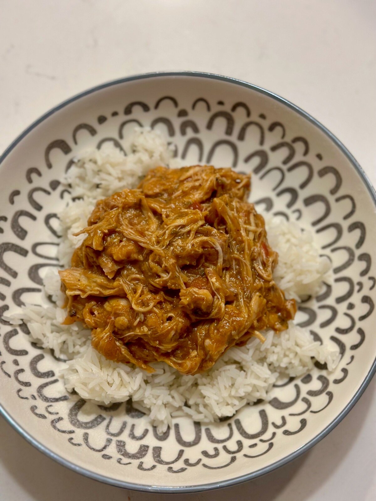 A bowl with white rice and a spoonful of drunken chicken