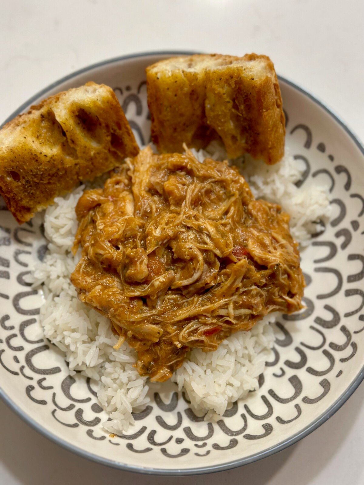 A bowl with rice, drunken chicken, and garlic bread