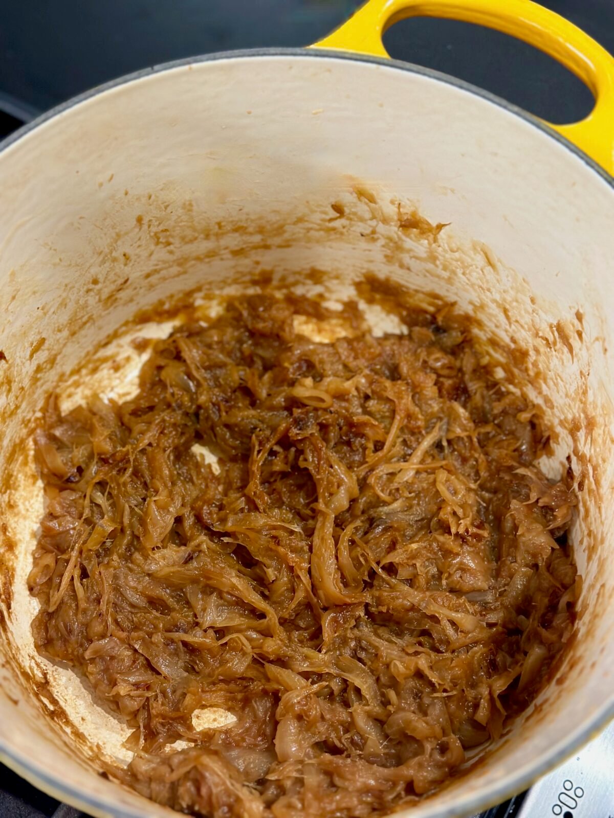 A yellow dutch oven with caramelized onions