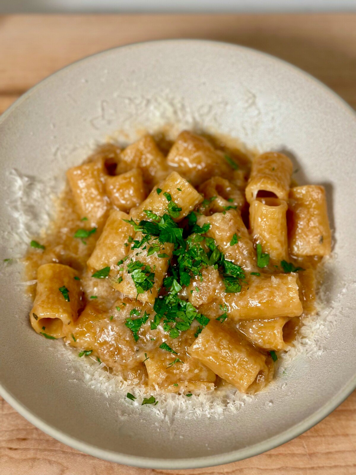 A white bowl with french onion pasta sprinkled with parmesan and parsley