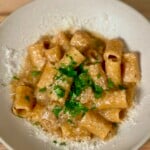 A white bowl with french onion pasta sprinkled with parmesan and parsley