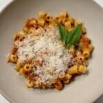 white bowl with ditalini pasta in a tomato sauce with parmesan cheese and basil