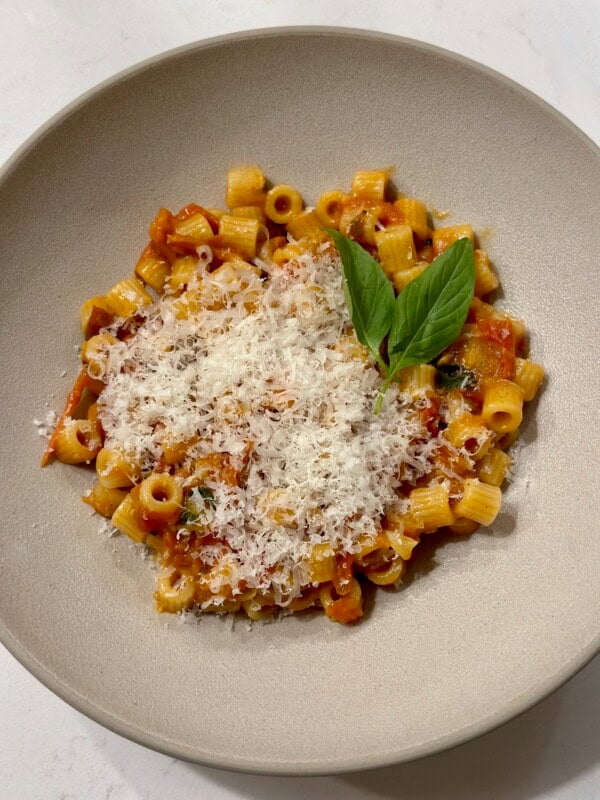 white bowl with ditalini pasta in a tomato sauce with parmesan cheese and basil