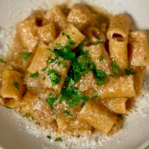 One pot french onion pasta in a bowl sprinkled with parsley and freshly grated parmesan cheese.