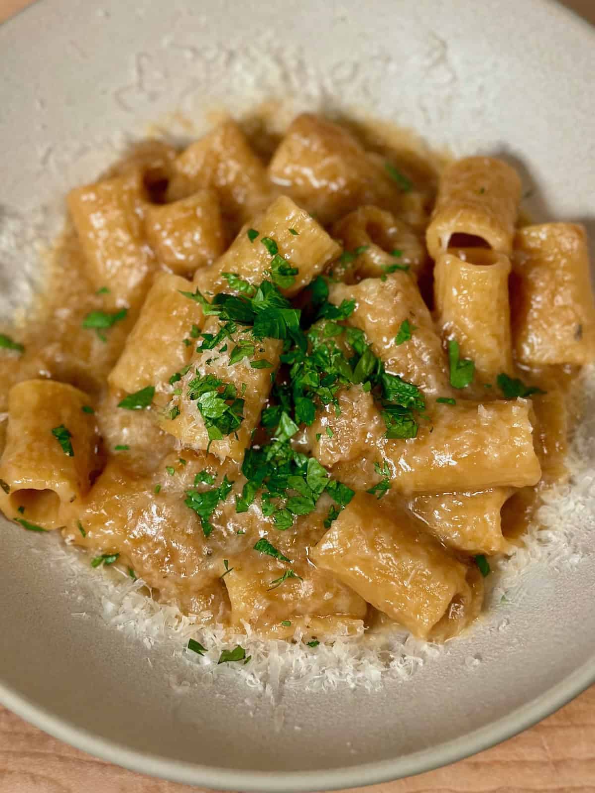 One pot french onion pasta in a bowl sprinkled with parsley and freshly grated parmesan cheese.