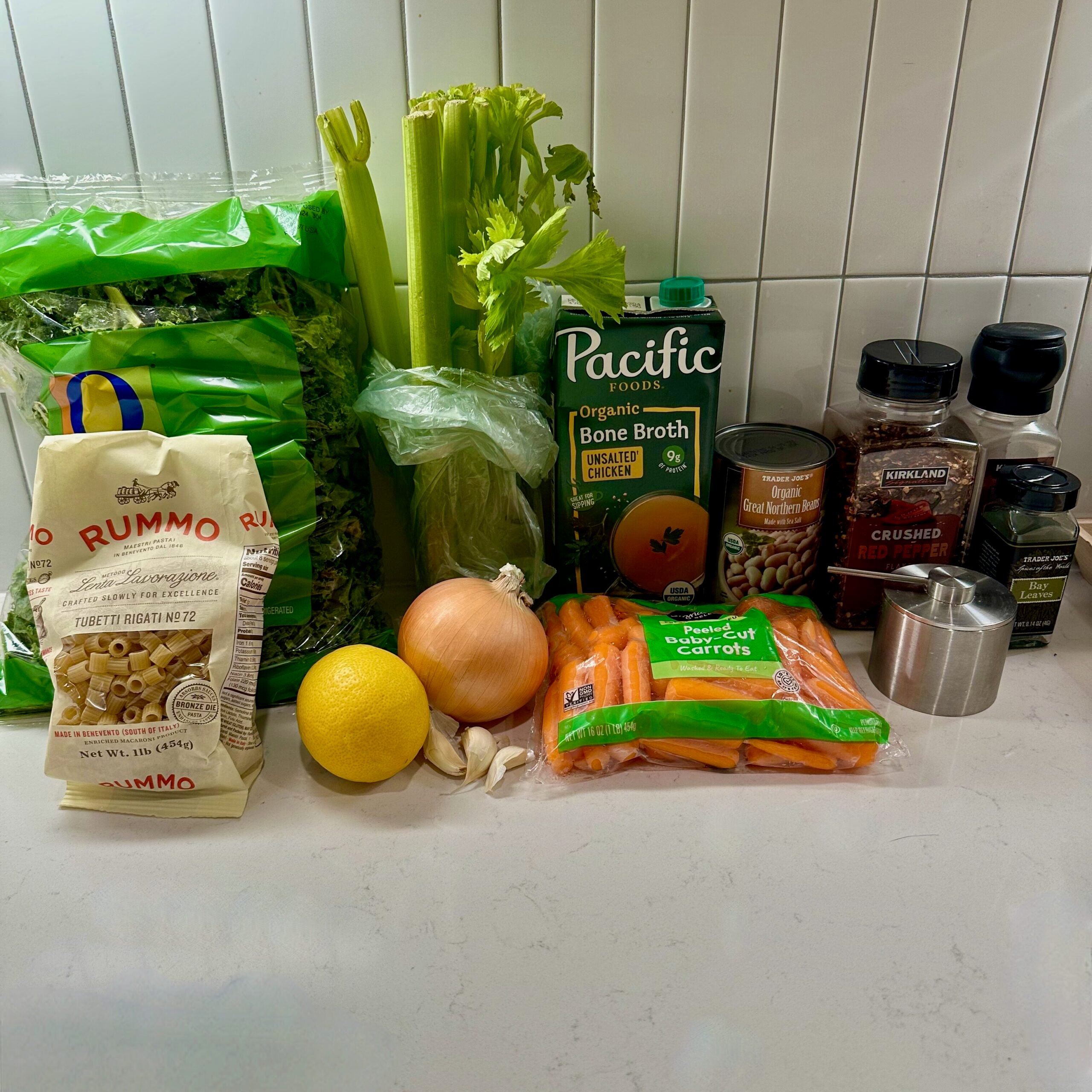 Mini meatball soup ingredients. Kale, ditalini pasta, celery, onion, carrots, garlic, lemon, red pepper flakes, white beans, salt, and black pepper.