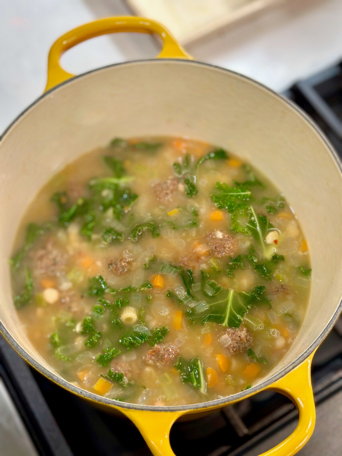 Yellow Dutch Oven with broth and wilted kale