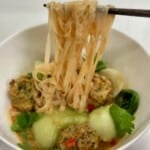 Thai Chicken Meatball Soup with noodle pull with chopsticks