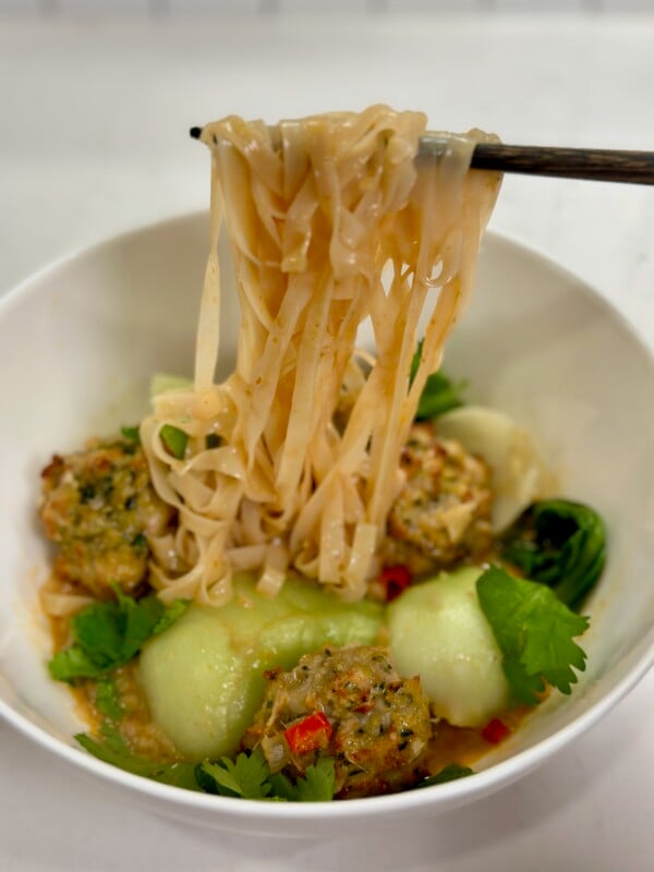 Thai Chicken Meatball Soup with noodle pull with chopsticks