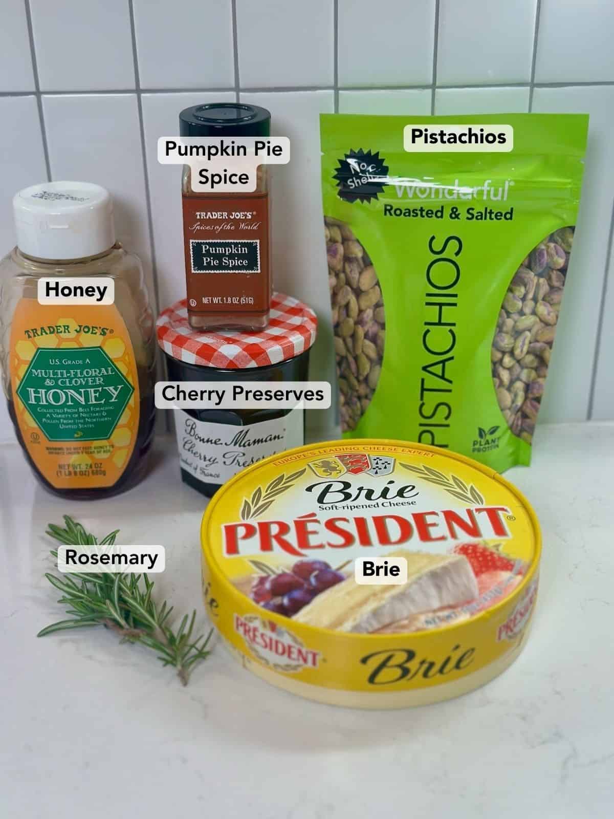 Ingredients for baked brie with cherry preserves and chopped pistachios arranged together.