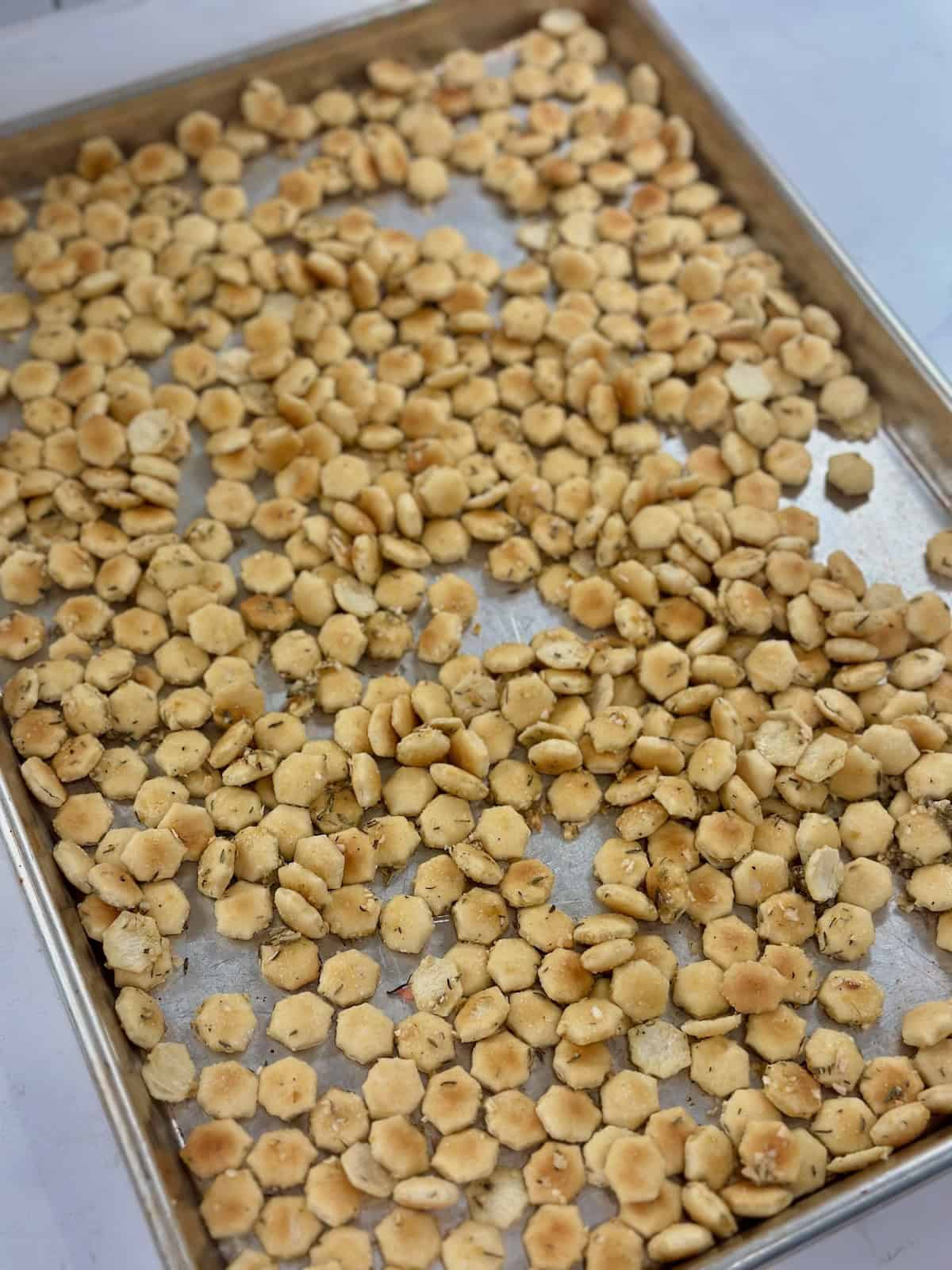 Seasoned French onion oyster crackers spread on a sheet pan before baking.