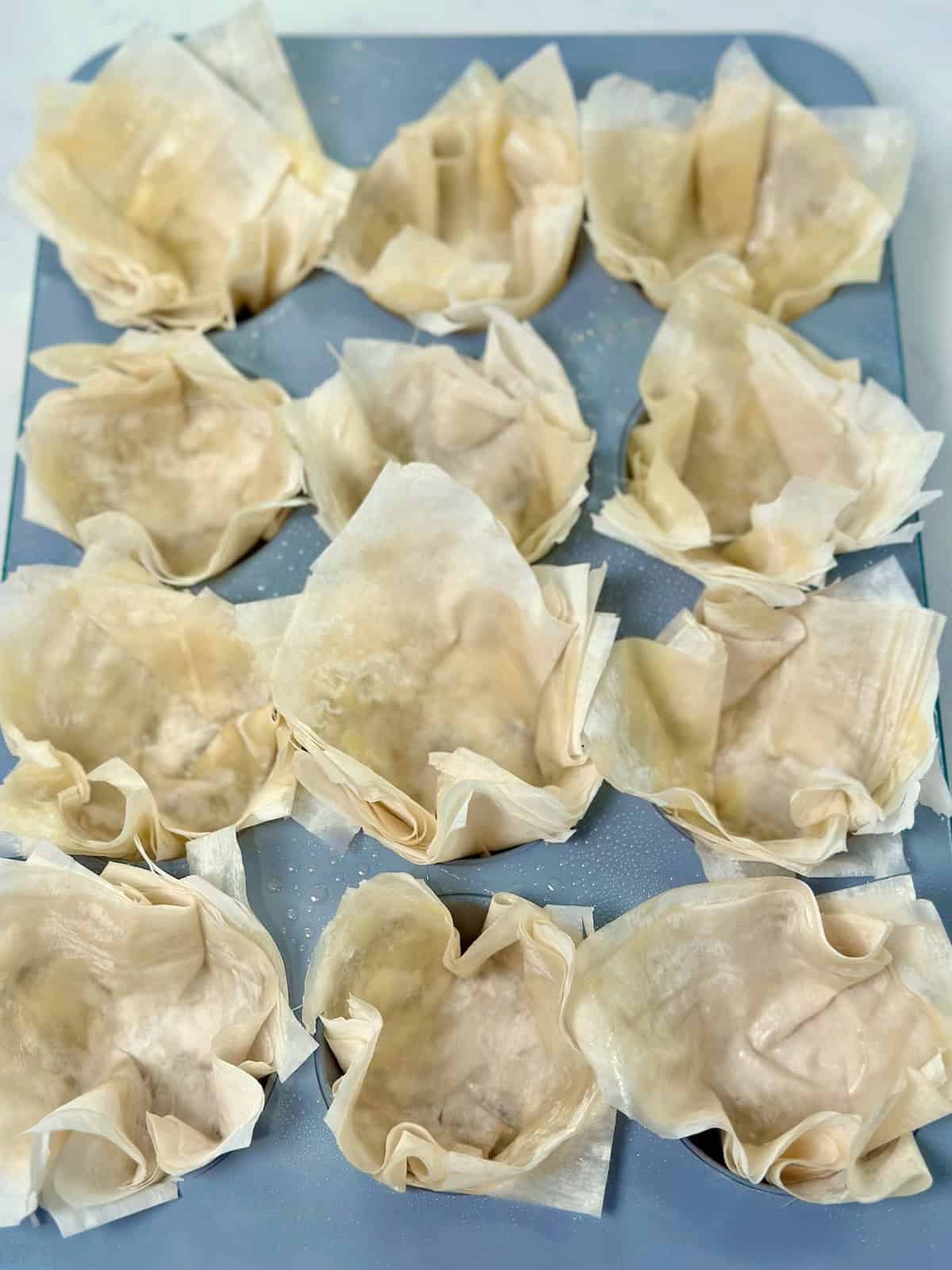 Phyllo dough cups formed in muffin tin before filling.