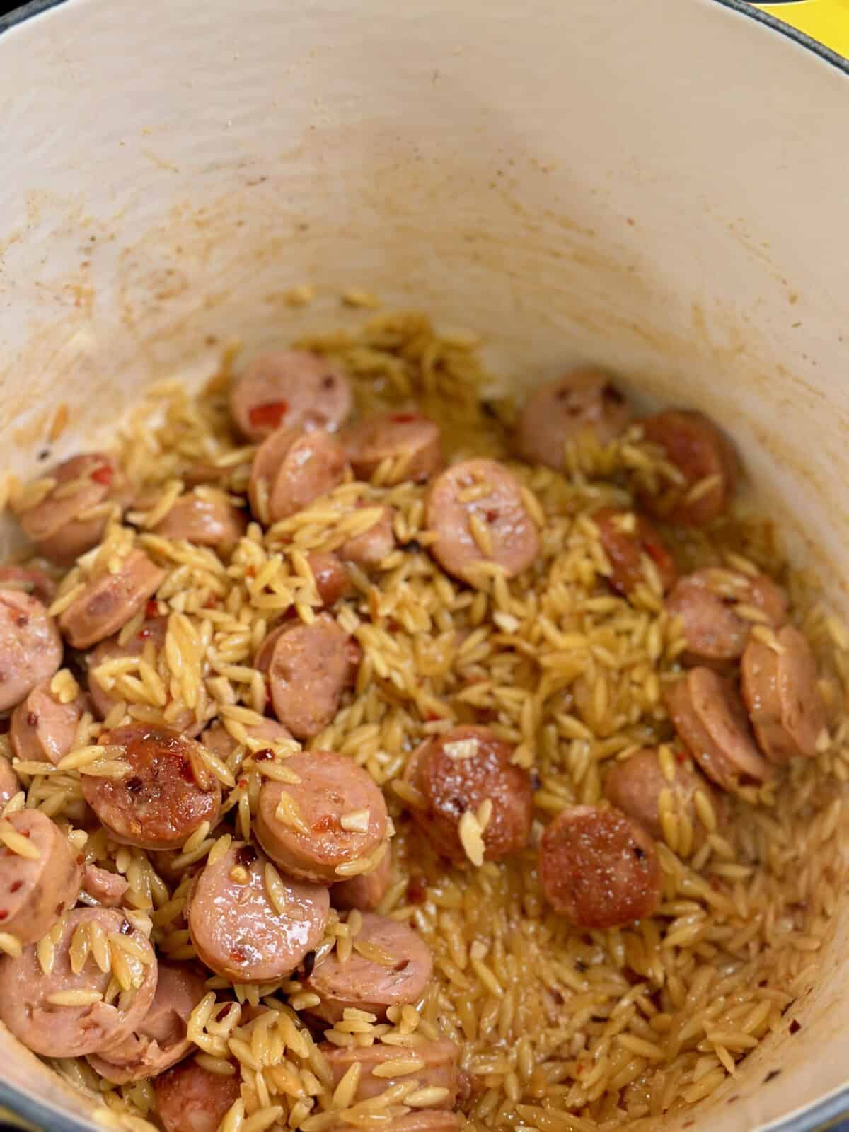 Cooked chicken sausage and orzo in a pot