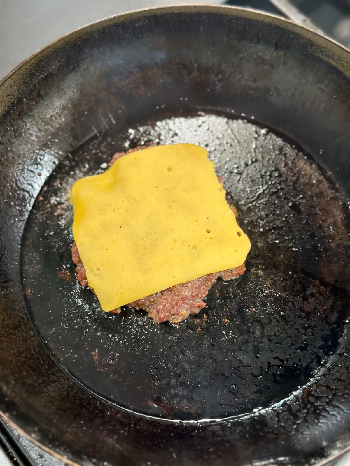 A pan with sausage patty with a slice of yellow cheese
