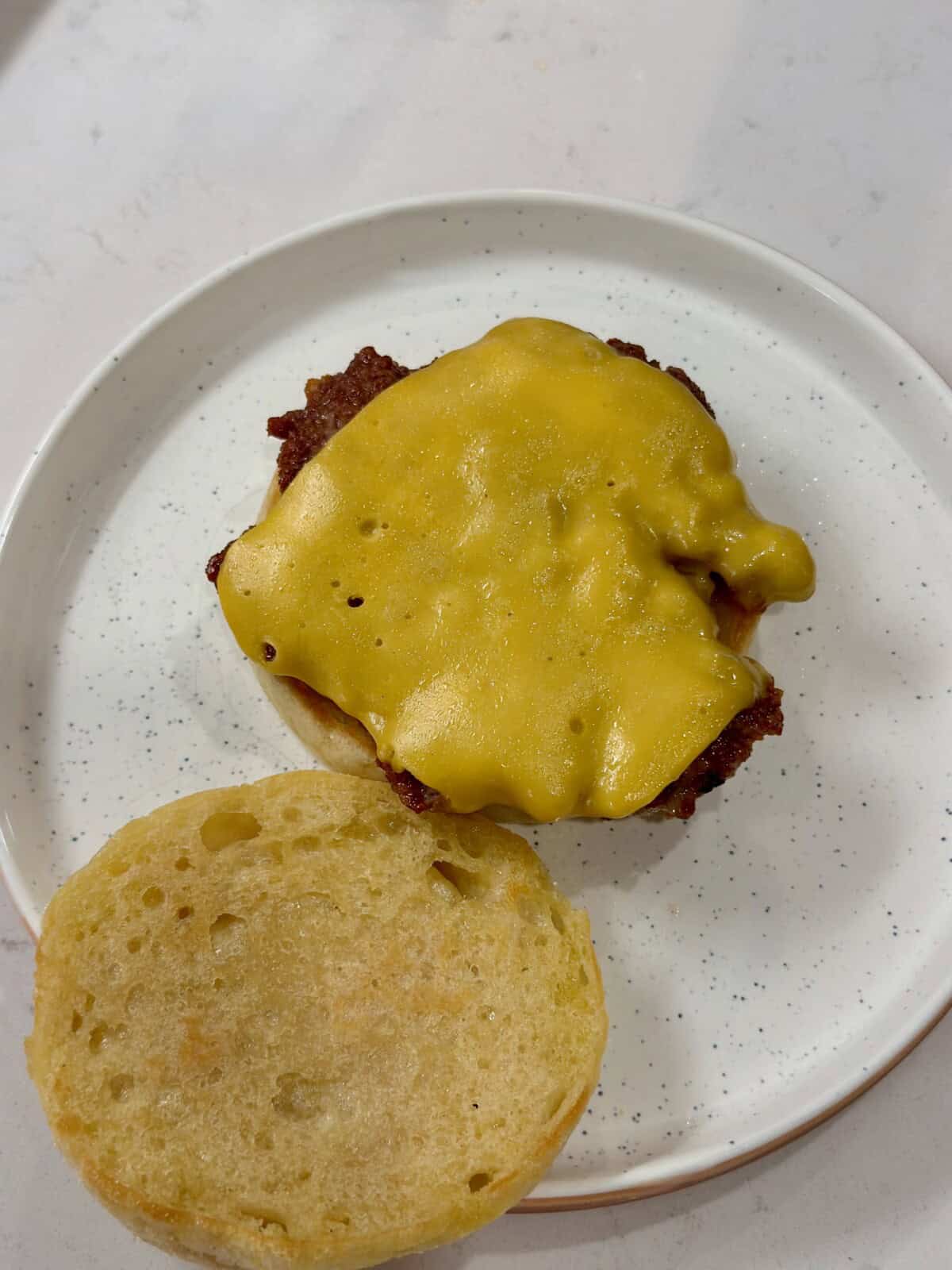 A plate with a sausage patty and melted cheese