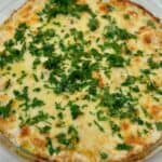 Baked chicken alfredo dip garnished with parsley.
