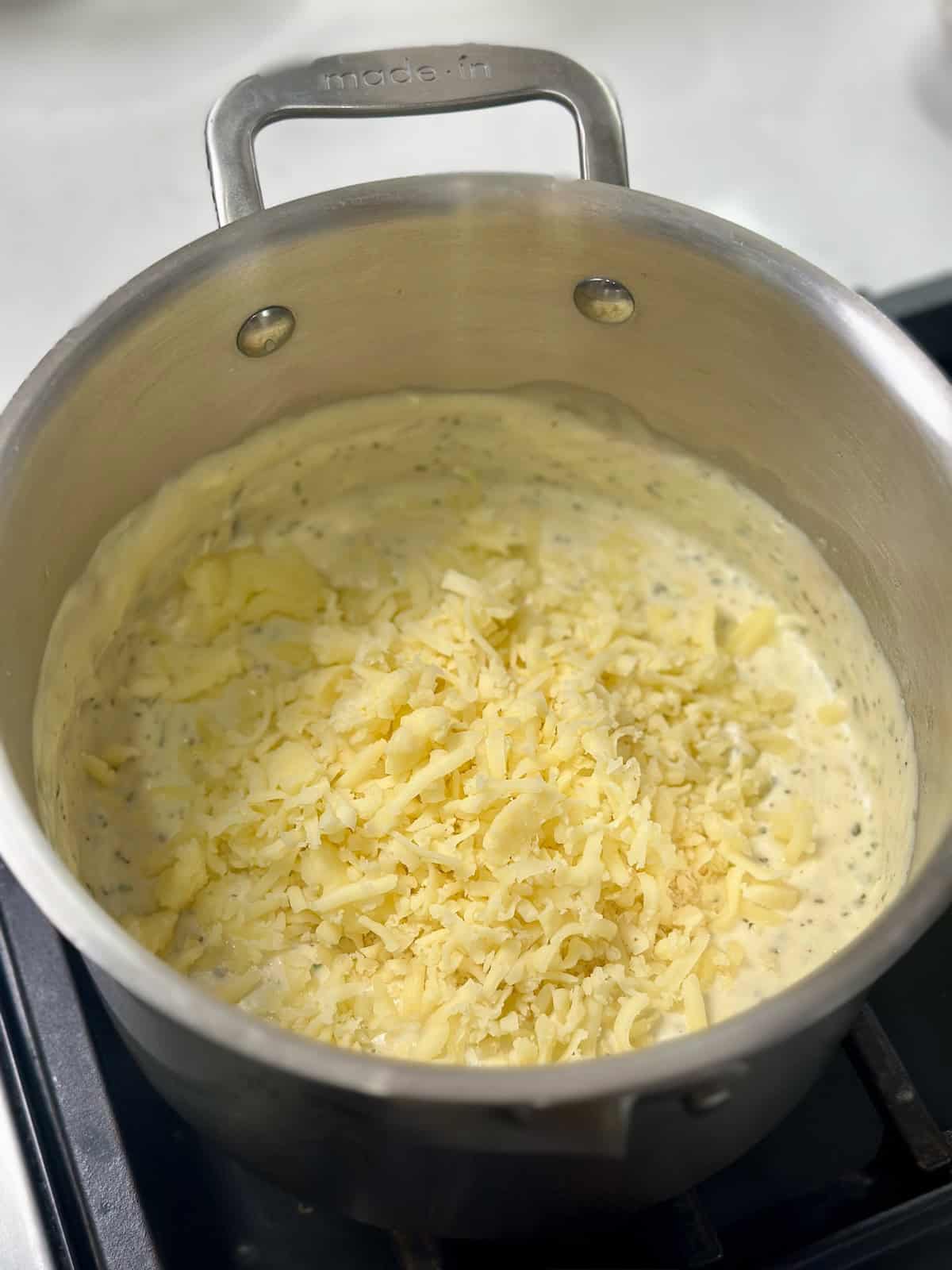 Cheese melting into a creamy alfredo sauce.