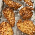 Golden crispy chicken cutlets resting on a wire rack after frying.