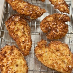 Golden crispy chicken cutlets resting on a wire rack after frying.