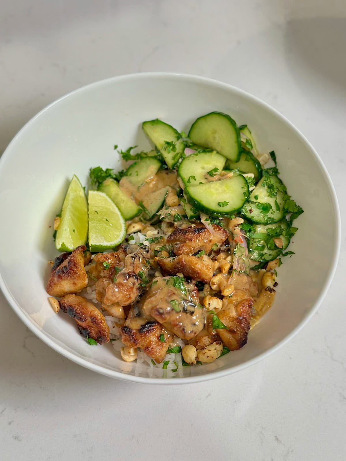 Thai peanut chicken served in a bowl with rice and vegetables.