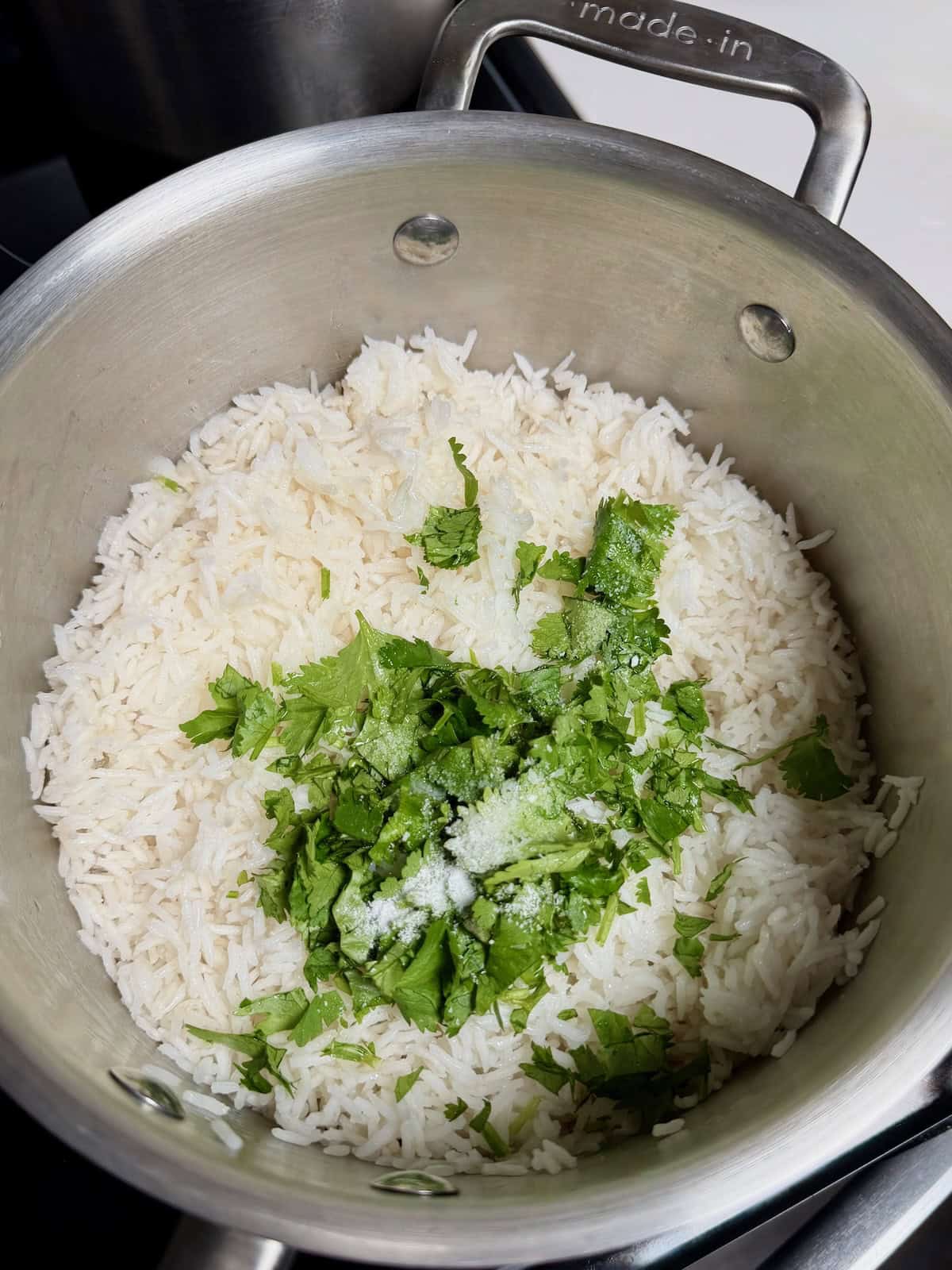 Adding fresh cilantro and citrus juice to cooked white rice.