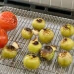 Broiled tomatillos, tomatoes, and garlic on wire rack on baking sheet.