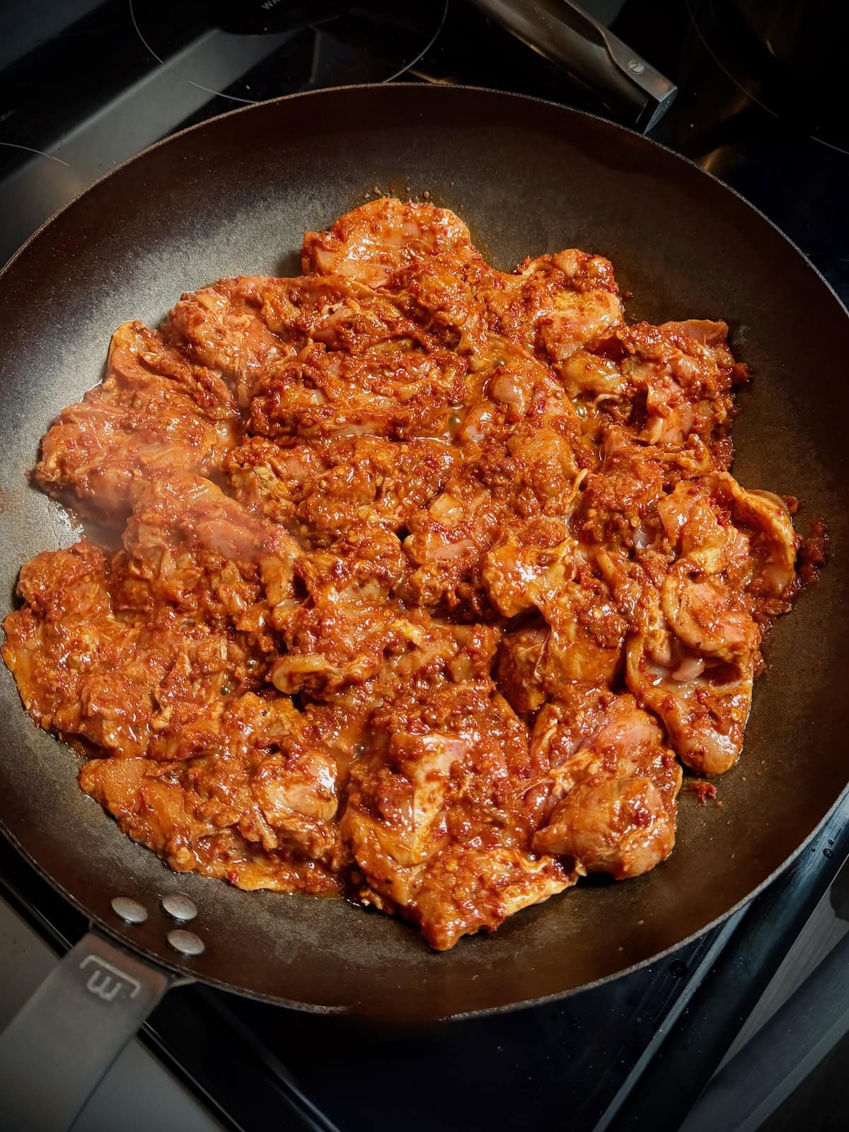 Marinated chipotle chicken thighs in carbon steel pan.