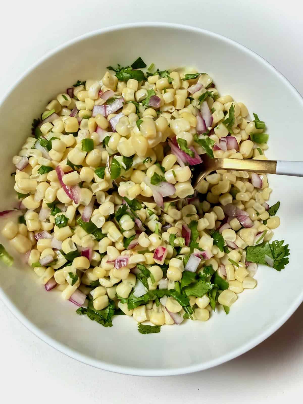 Chipotle copycat corn salsa in bowl on a spoon.