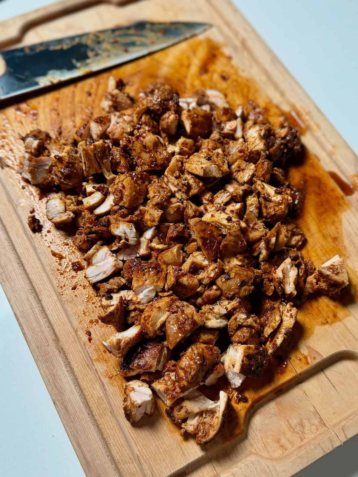 Chipotle copycat chicken cut into small pieces on wooden cutting board.