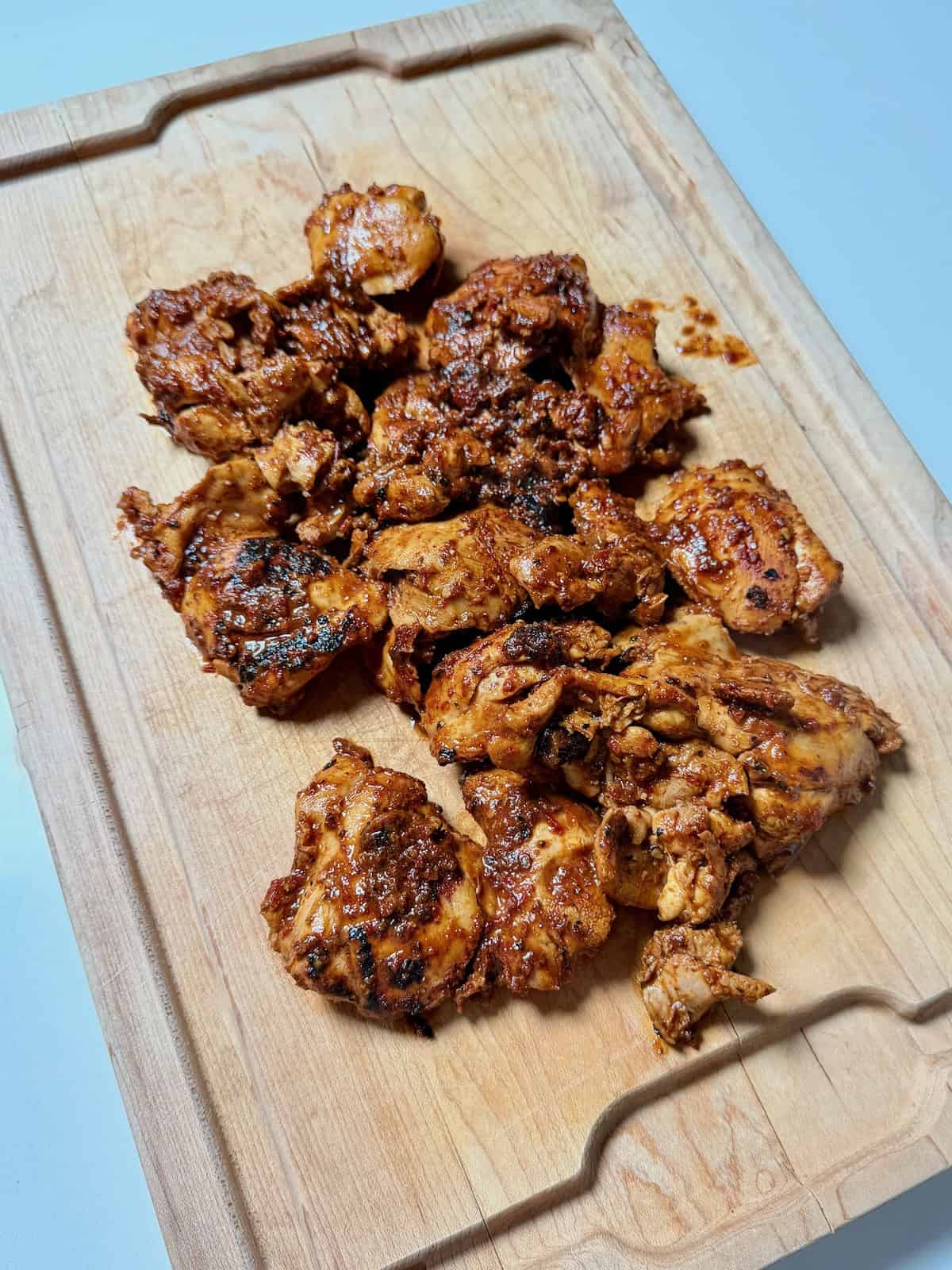 Cooked chipotle copycat chicken thighs on cutting board.