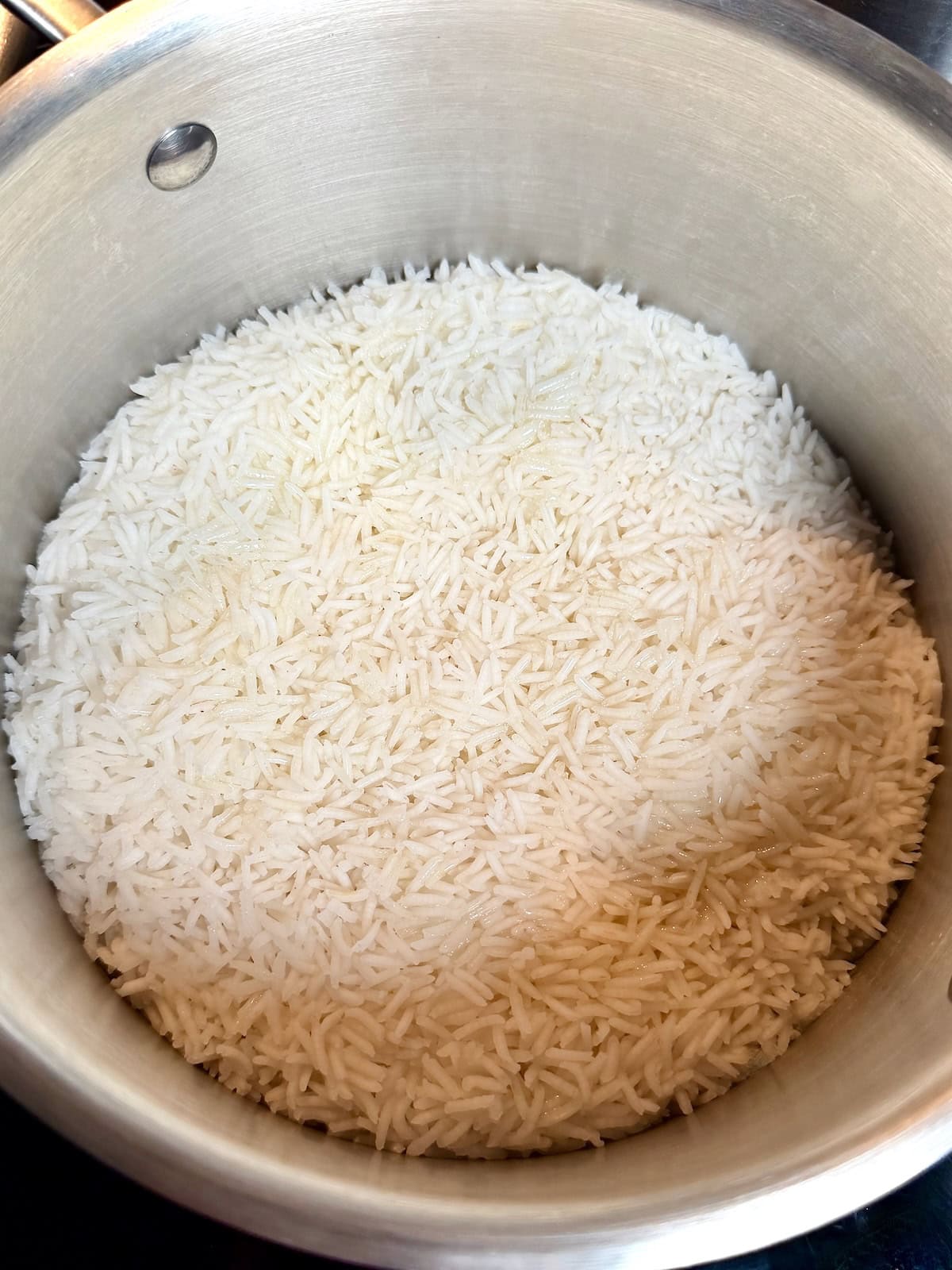 Cooked long grain white rice in a pot after steaming.