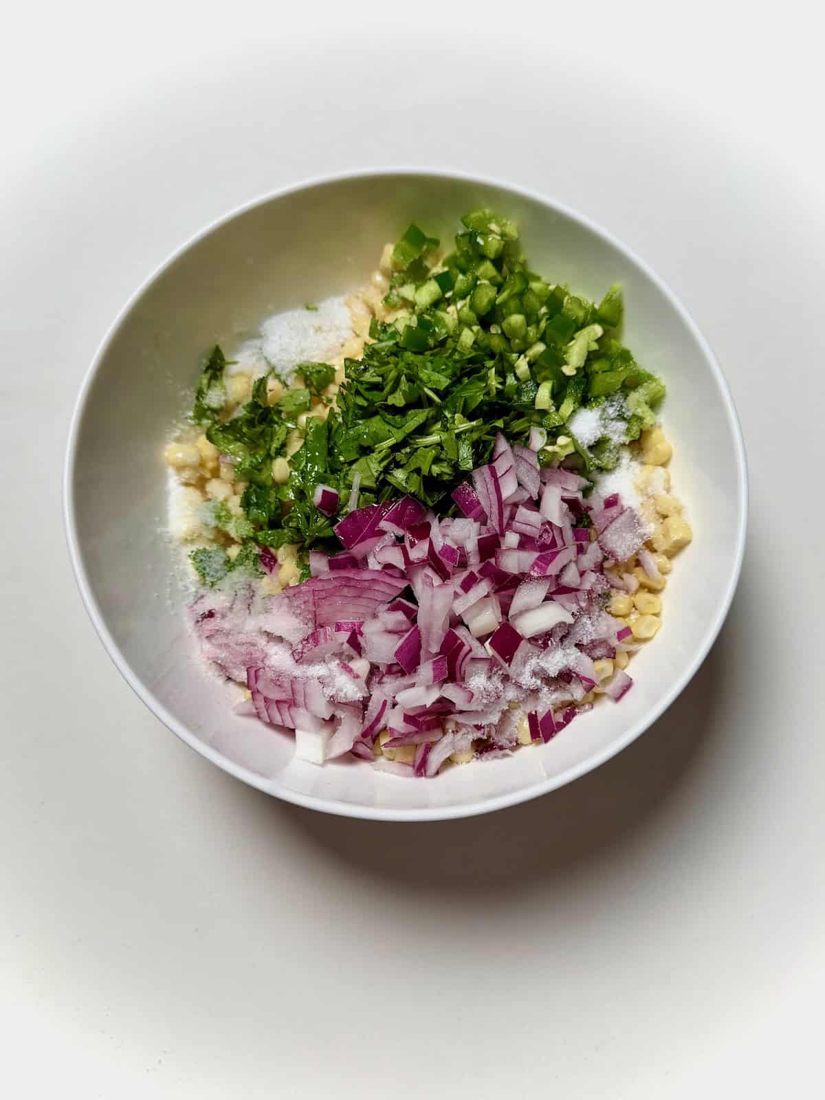 Chopped ingredients for corn salsa in bowl.