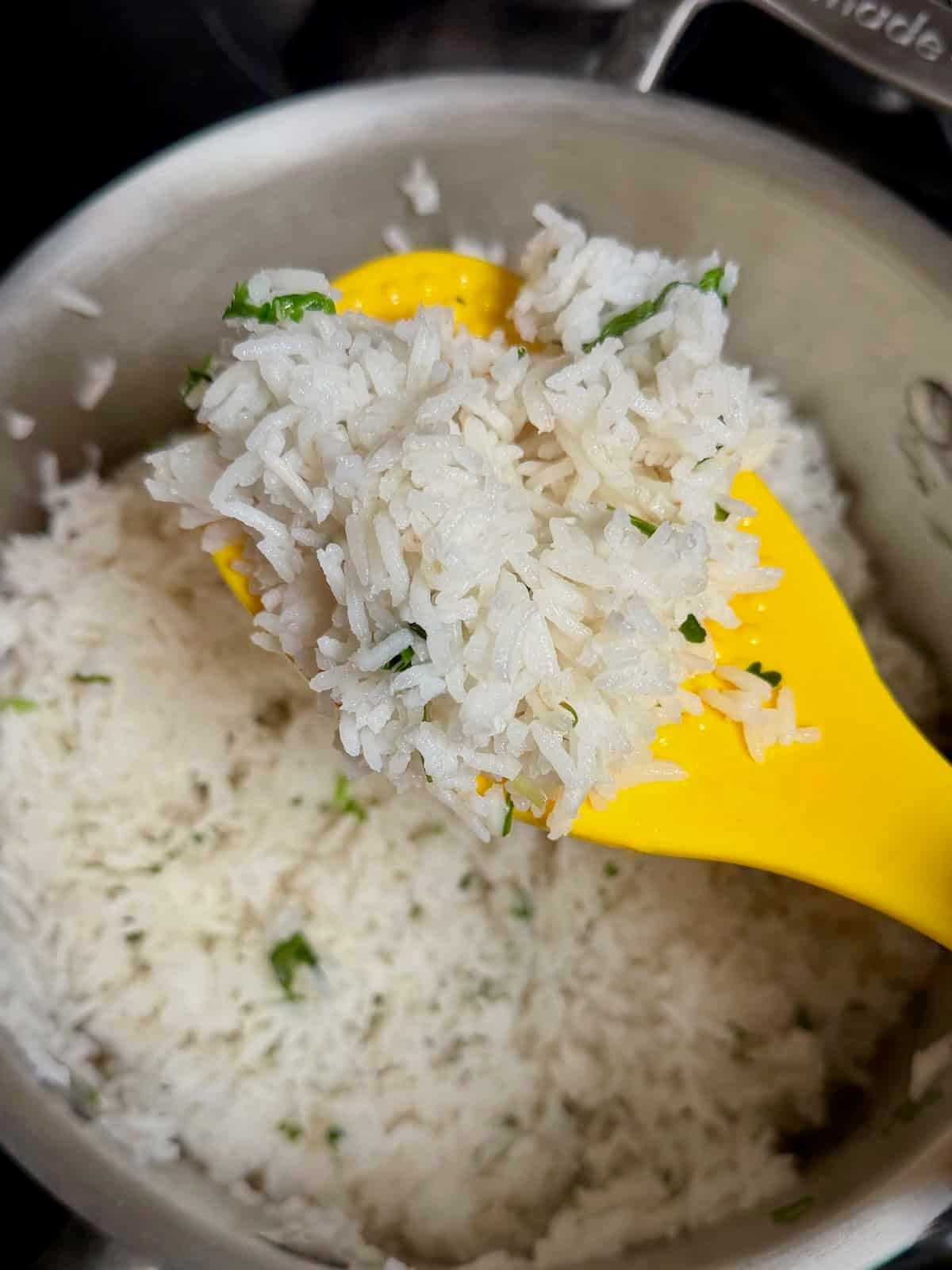 Fluffing cilantro lime rice with a spatula after seasoning.