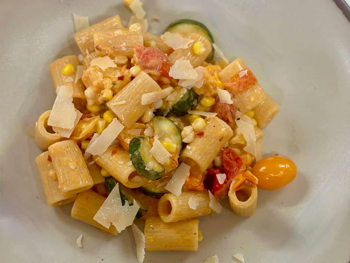 A bowl with Summer Pasta with Zucchini, Corn, and Tomatoes