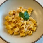 A bowl of creamy orange tomato pasta with parmesan cheese and fresh basil