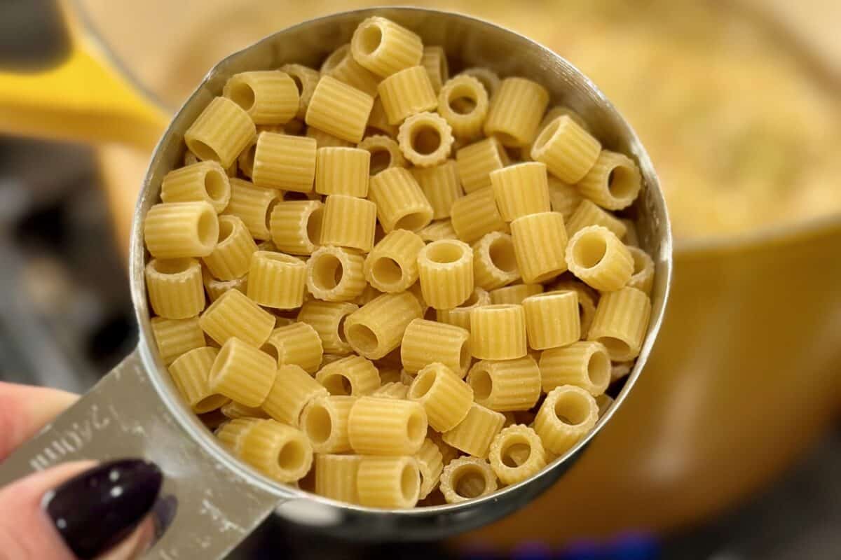Measuring cup with uncooked ditalini pasta.