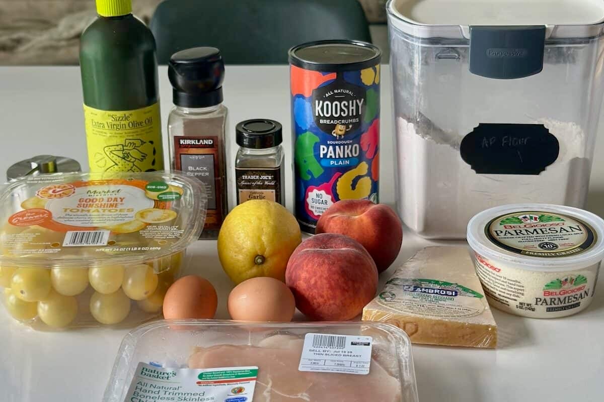 Ingredients for Chicken Milanese with peach and tomatoes on the counter