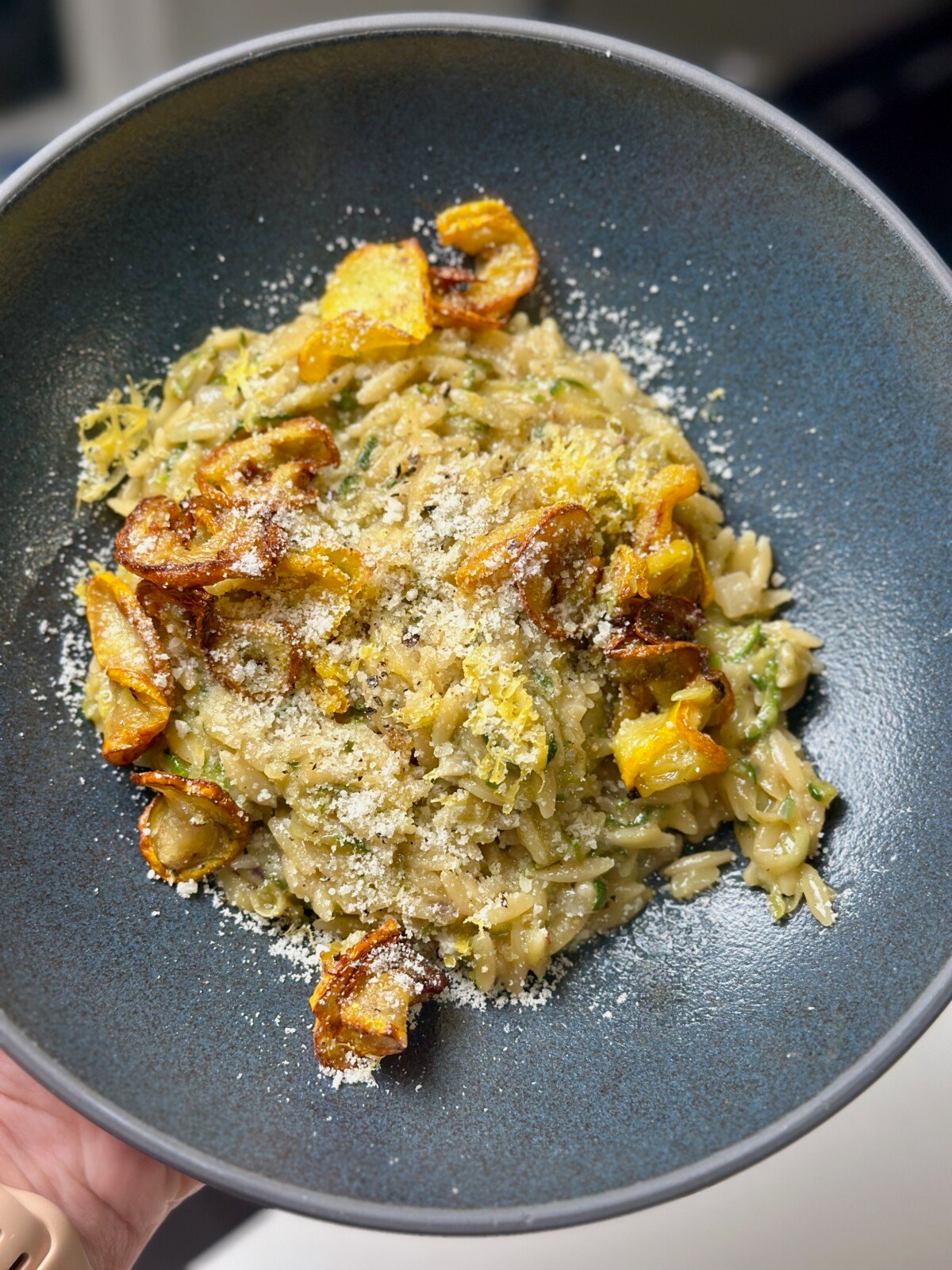 Holding Creamy Zucchini Orzo in Blue Bowl