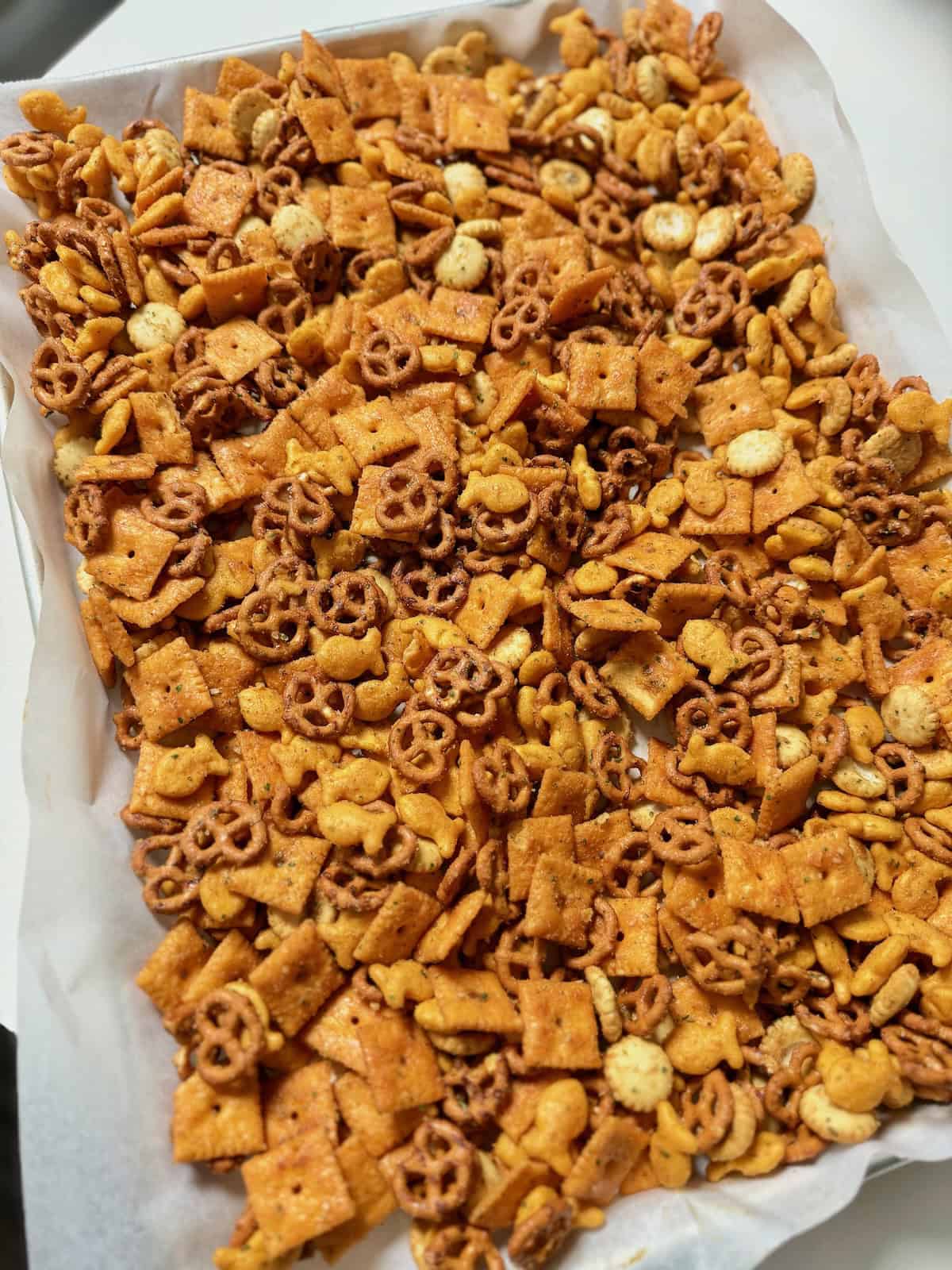 Unbaked Cheez-It ranch snack mix spread evenly on a parchment-lined baking sheet.