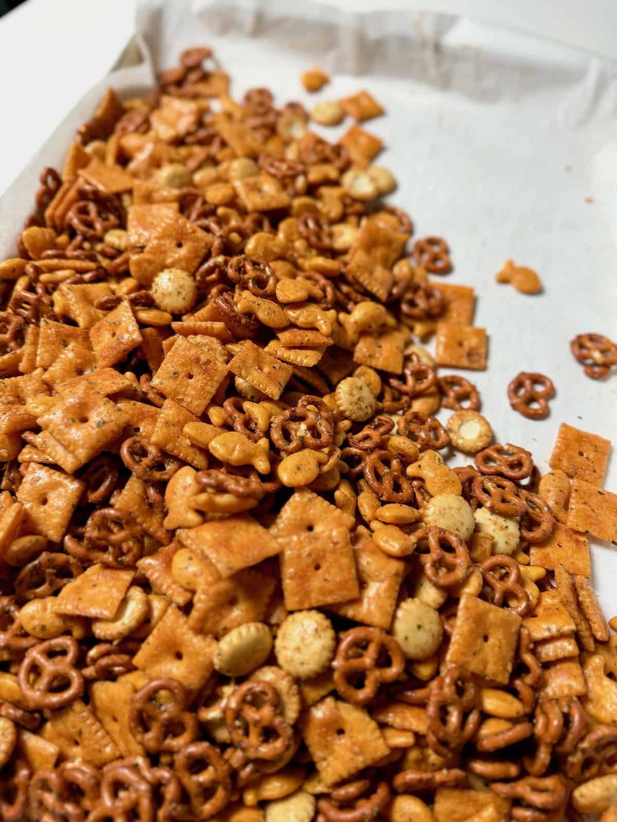 Close-up of baked Cheez-It ranch snack mix with golden crackers and pretzels.