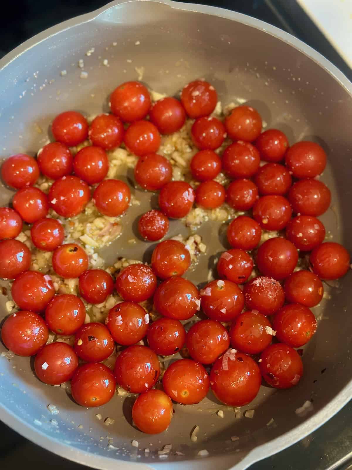 Cherry tomatoes added to a skillet with shallots, garlic, butter, and olive oil.