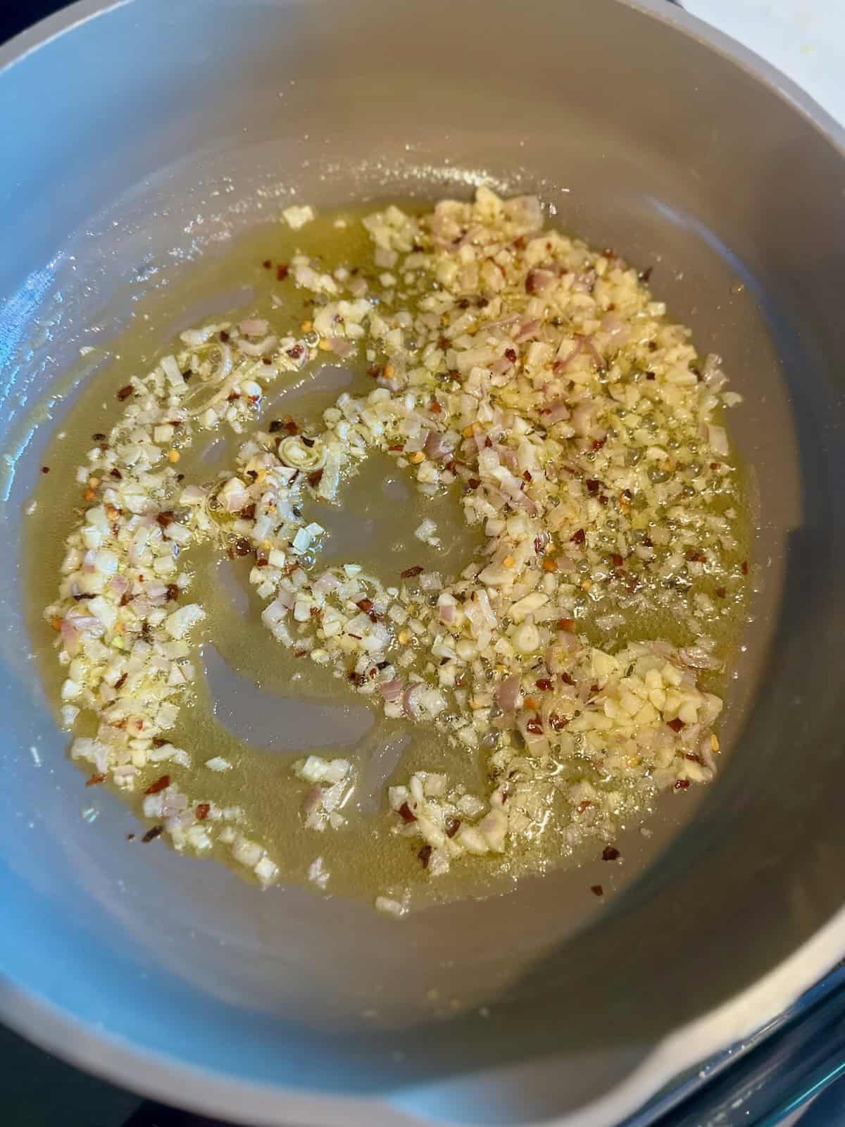 Shallots, garlic, and red pepper flakes cooking in butter and olive oil for Tomato Basil Shrimp Pasta.