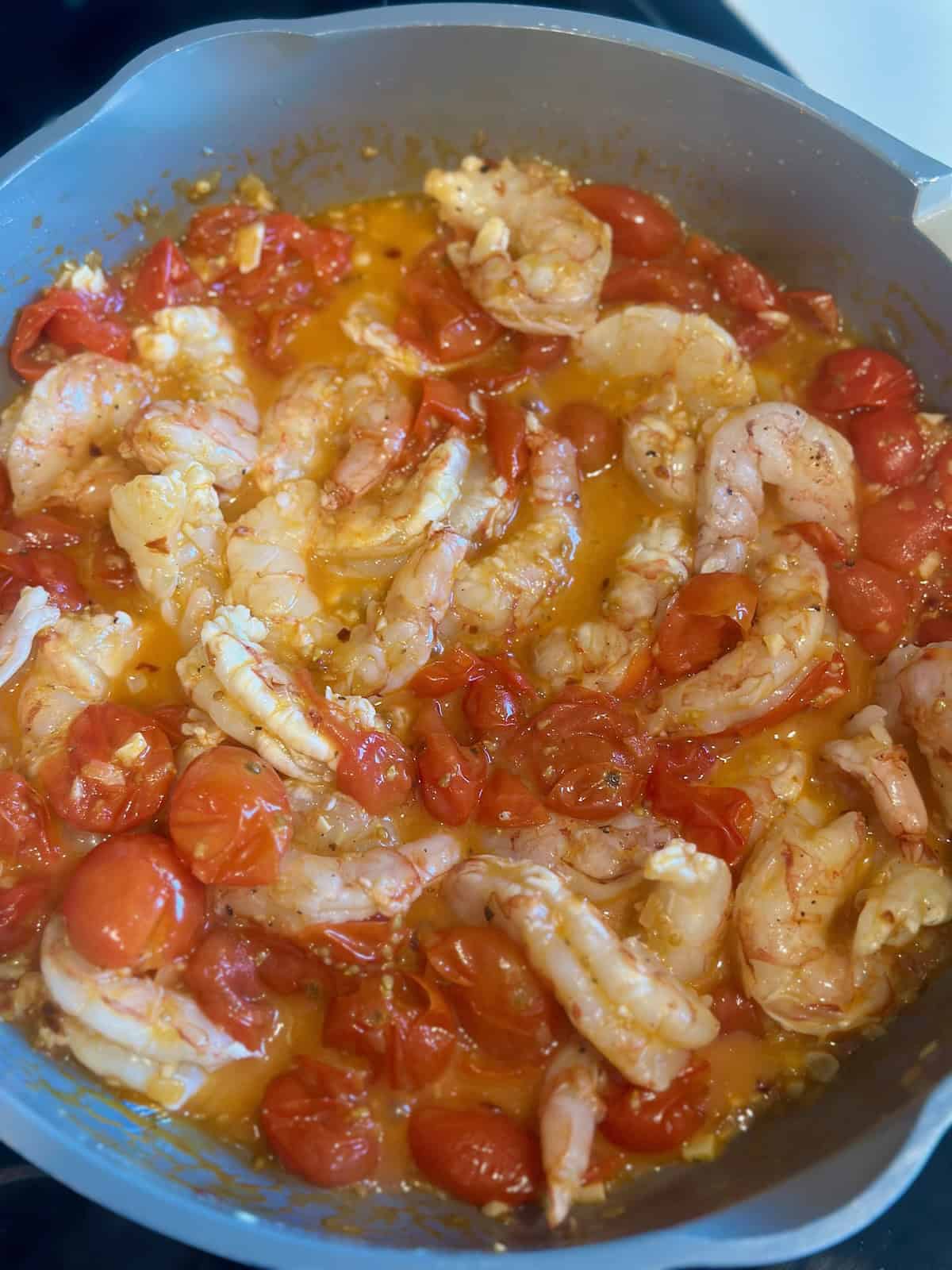 Shrimp cooking in a burst cherry tomato sauce for Tomato Basil Shrimp Pasta.