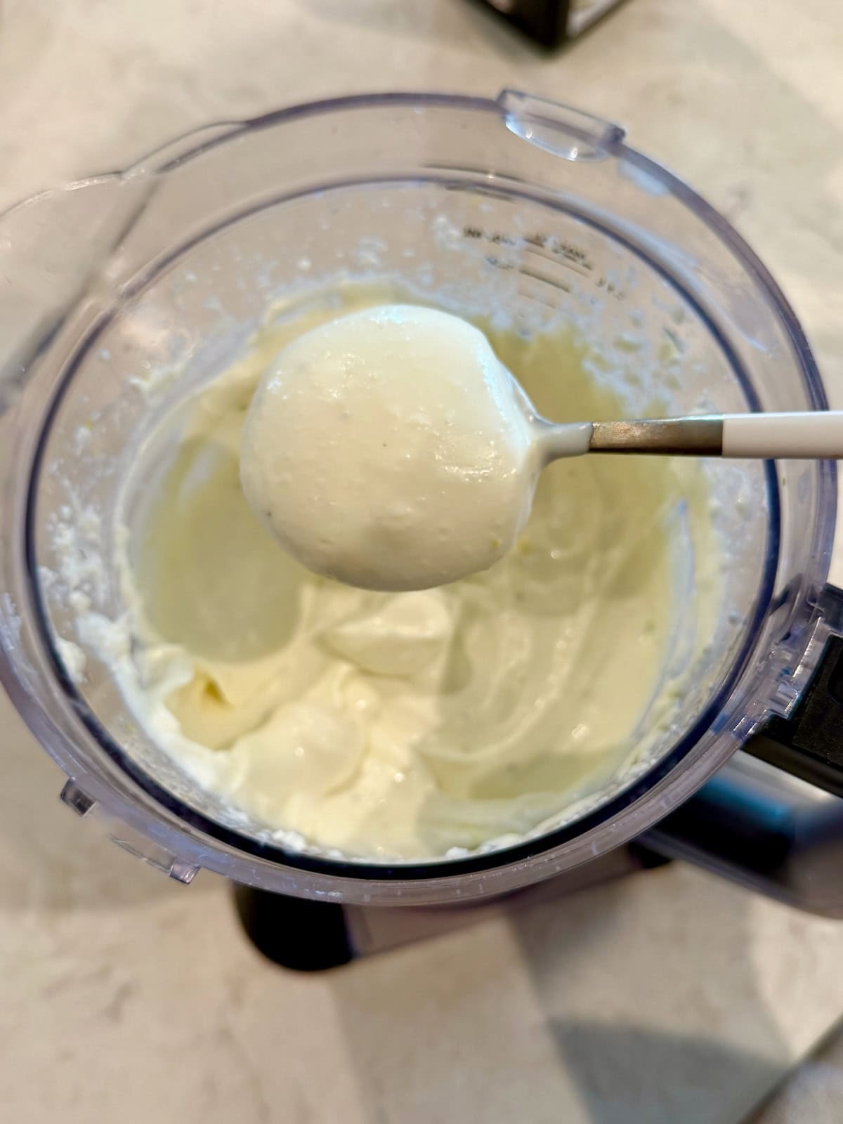 Smooth whipped ricotta in a food processor and on spoon.