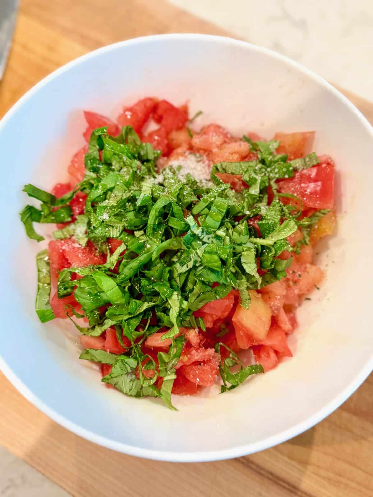 Diced tomatoes and fresh basil in a bowl for bruschetta topping before mixing.