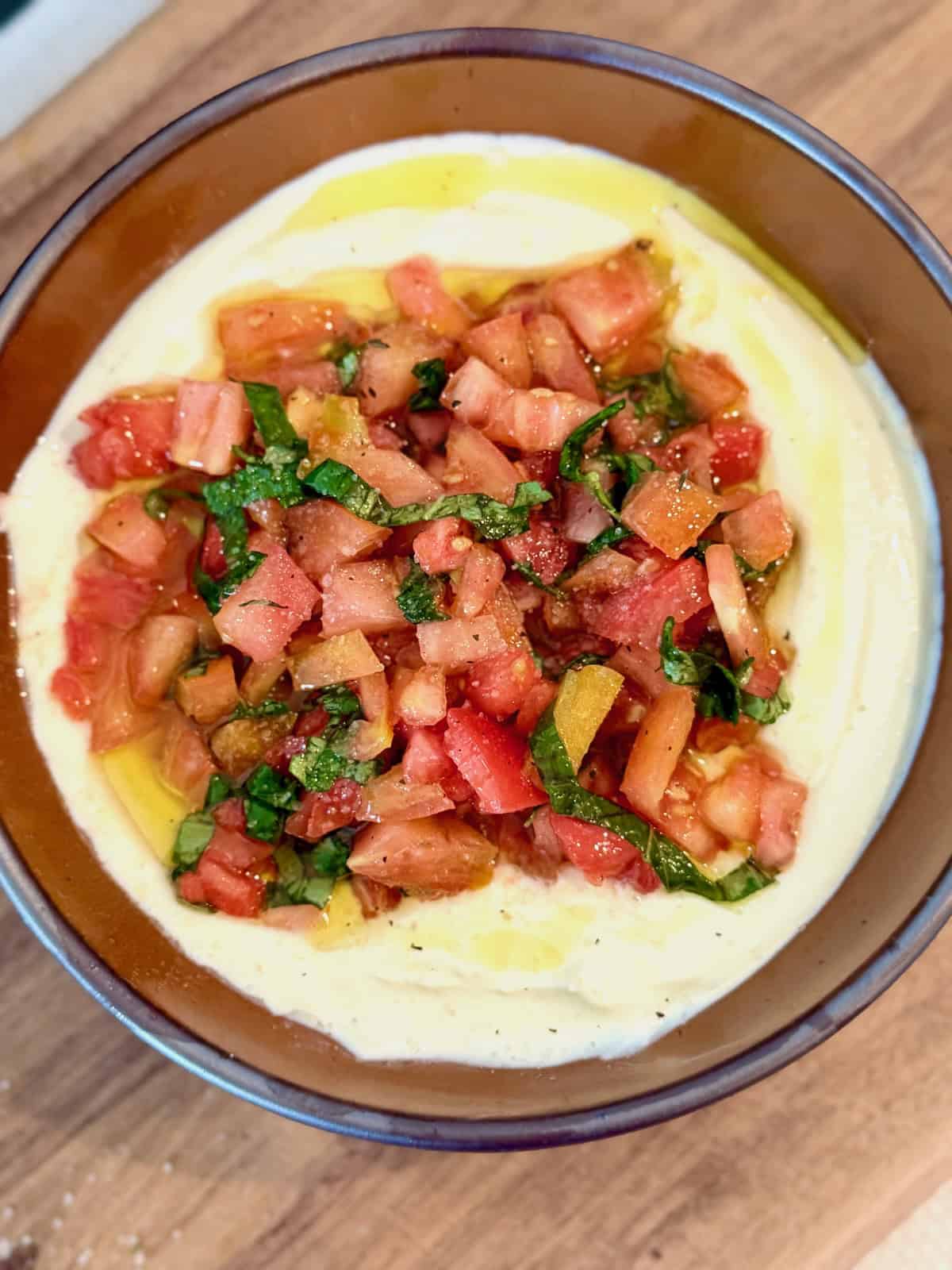 Whipped ricotta bruschetta dip topped with tomatoes and basil.