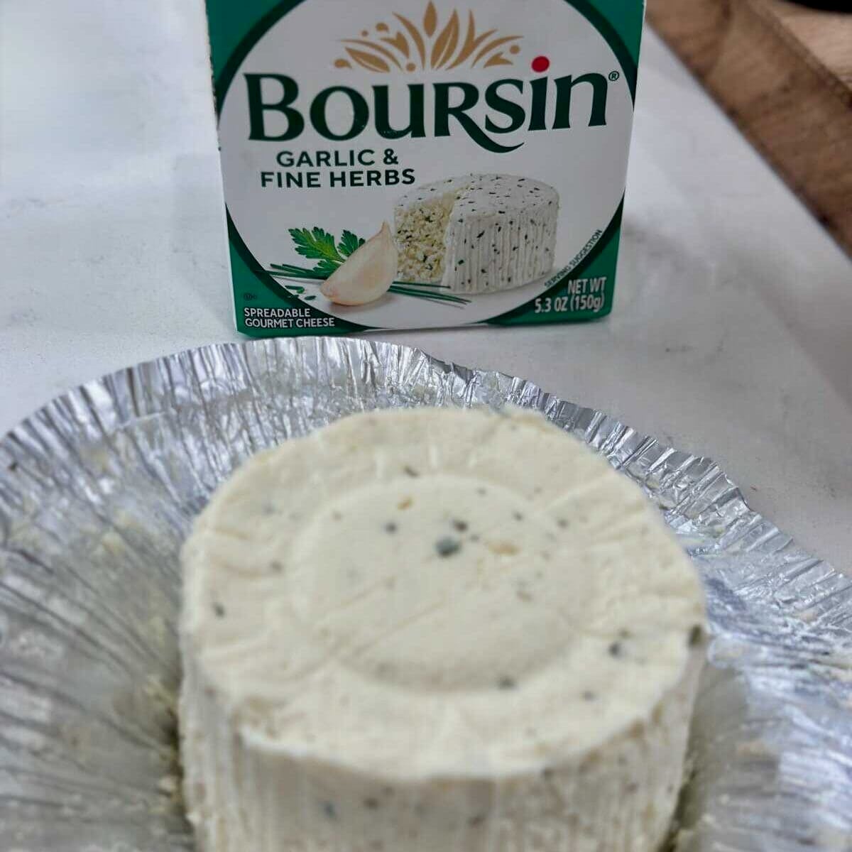 Boursin cheese in the wrapper next to the box.