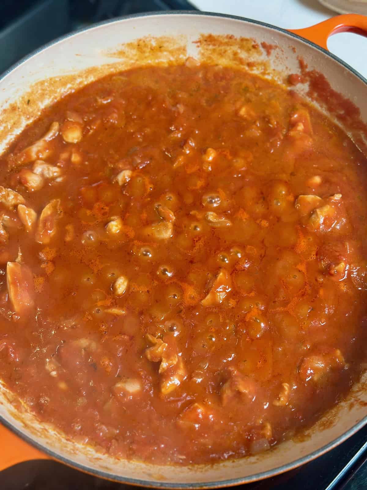 Chicken tikka masala sauce for pasta simmering in orange pan.