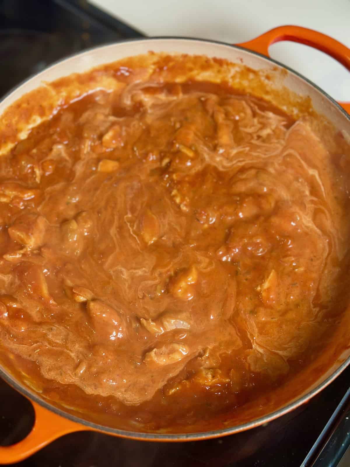 An orange braiser with creamy chicken tikka masala.